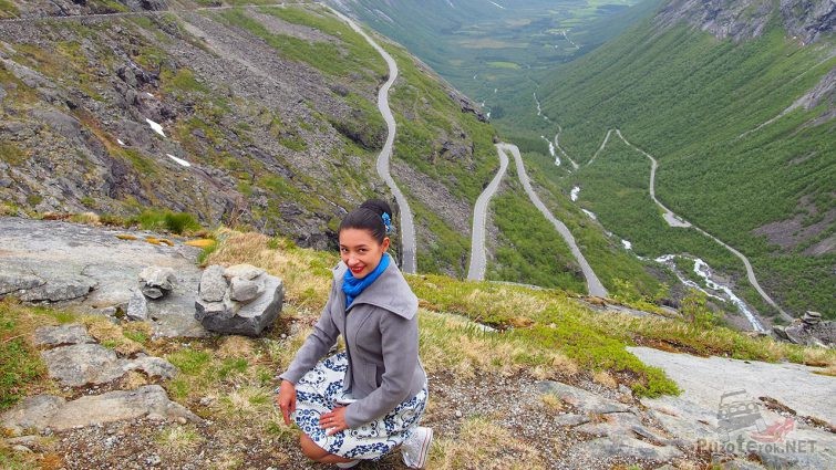 Туристка позирует на фоне серпантина горного перевала Дорога Троллей в Норвегии
