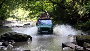 Туристы на джиппинге в Абхазии едут по руслу горной речки