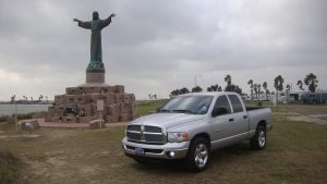 Серый Dodge Ram возле статуи Исуса