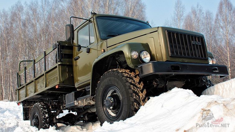 Военный грузовик взбирается по снегу на горку