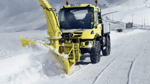 Жёлтая спецтехника убирает снег на дороге