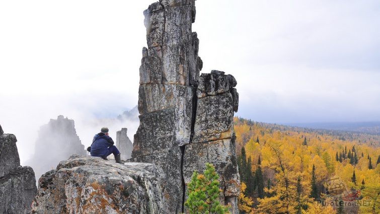 Турист сидит на высокой скале