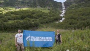 Туристы с корпоративным флагом на фоне водопада
