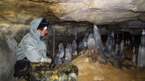 Спелеотурист любуется на сталактиты и сталагмиты из льда