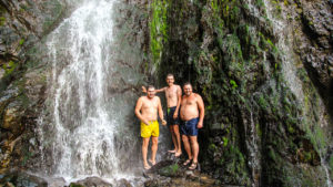 Туристы под холодными струями водопада